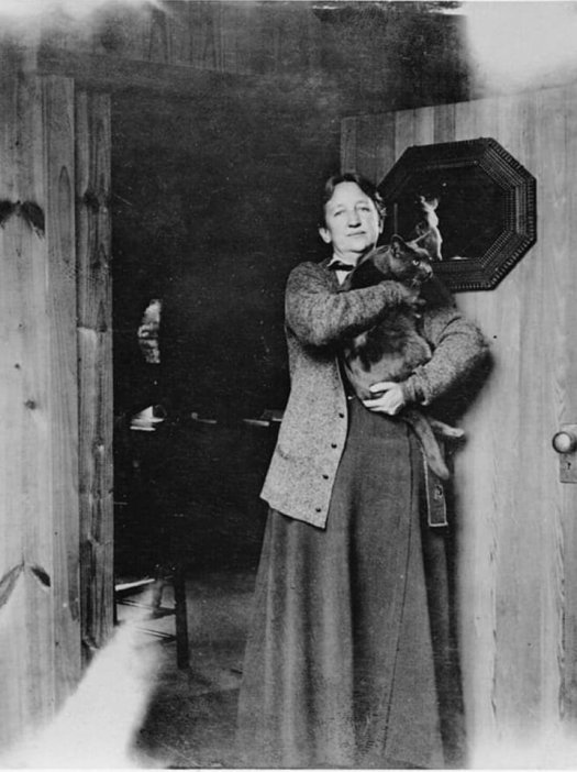 Rockefeller Archive Center Mary Richmond (Director of Charity Organization Department of Russell Sage Foundation) Mary Richmond holding a cat and standing in front of a small mirror attached to a door. 