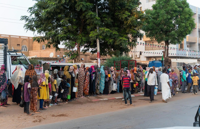 Familias desplazadas recientemente de El Fasher hacen fila en un reparto de alimentos, junto a residentes de larga duración, en Omdurman, la segunda mayor ciudad de Sudán.  © ACNUR/Ala Kheir